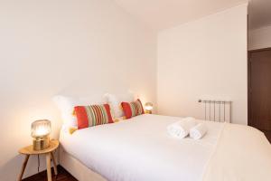 a bedroom with a large white bed with towels on it at Braga 3BR Wonder by LovelyStay in Braga