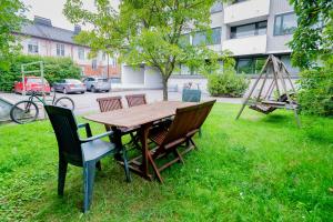 een houten tafel en stoelen in het gras met een schommel bij White House 61m2 Alppila Helsinki in Helsinki