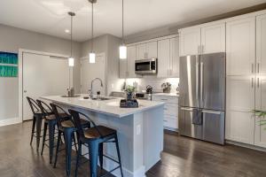 a kitchen with white cabinets and a large island with bar stools at Downtown Condo City Center in Asheville