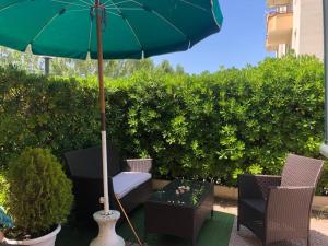 a patio with a green umbrella and chairs and a table at L'angolo della felicità in Marina di Montenero