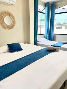 Duas camas num quarto com cortinas azuis e um espelho em Reef Hostel Manta em Manta