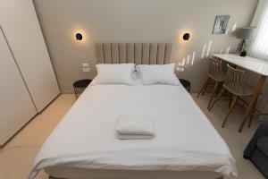 a large white bed in a room with a table at Carmel Studio By Carmel Boutique in Haifa
