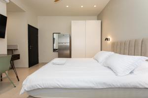 a bedroom with a white bed and a refrigerator at Carmel Studio By Carmel Boutique in Haifa