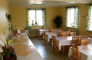 un comedor con mesas y sillas blancas y ventanas en Folsom en Årjäng