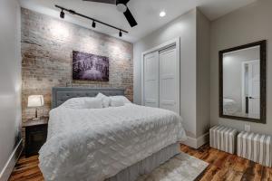 a bedroom with a white bed and a brick wall at Fabulous Downtown 2 bedroom Condo in Asheville