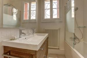 La salle de bains blanche est pourvue d'un lavabo et d'une douche. dans l'établissement Le Meulière, à Viroflay