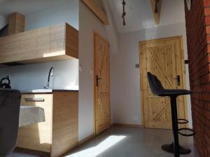 a kitchen with wooden doors and a stool in a room at Apartament Julia in Maniowy