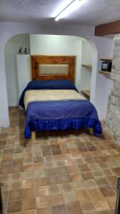 a bedroom with a bed with a blue comforter at Hotel Magdalena Colonial in Guanajuato