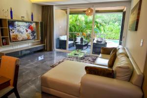 sala de estar con sofá y ventana grande en Luxurious Apartments With BBQ Pool Garden Jungle View en Akumal