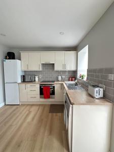 cocina con electrodomésticos blancos y suelo de madera en Tully's Home, Tulfarris Village, Wicklow, en Blessington