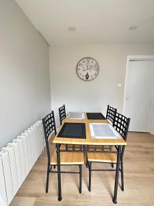 uma mesa de jantar com cadeiras e um relógio na parede em Tully's Home, Tulfarris Village, Wicklow em Blessington