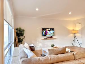 a living room with a couch and a tv on a wall at Rosebud Lovely House 2 - Mornington Peninsula 4 BR 3 Bath 2 story holiday house - BBQ - Beach - Hot spring in Rosebud