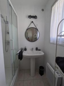 La salle de bains blanche est pourvue d'un lavabo et d'un miroir. dans l'établissement Chambre d'hôte au cœur des Alpilles, à Mouriès