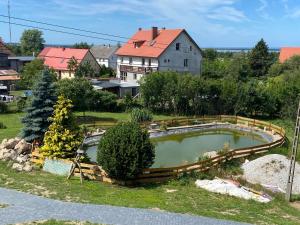 a pond in a yard with a house in the background at Agroturystyka Barzowice in Darłowo