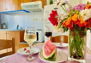 Nitsa's Apartments في Megálon Choríon: طاولة مع إناء من الزهور وكأس من النبيذ