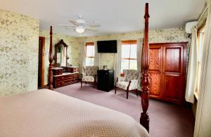 a bedroom with a bed and a desk and chairs at Rose Farm Inn in New Shoreham