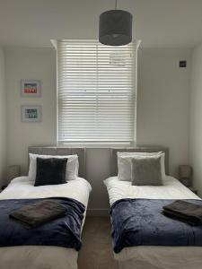 two beds in a room with a window at Beachside Mews in Broadstairs
