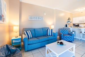 a living room with a blue couch and a table at Tradewinds #1208 in Orange Beach