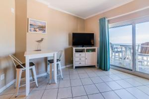 a living room with a desk and a television and a balcony at Tradewinds #1208 in Orange Beach