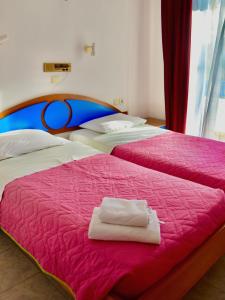 2 bedden in een kamer met een roze sprei bij Nitsa's Apartments in Megálon Choríon