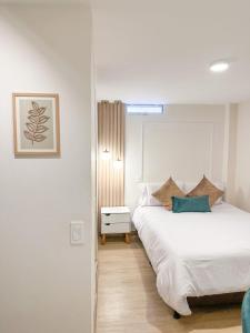 a white bedroom with a bed and a window at Hotel Santa Elena Norte in Tunja