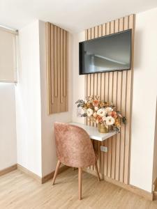a table with a chair and a television on a wall at Hotel Santa Elena Norte in Tunja +46 photos