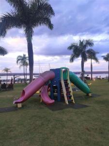 um parque infantil com escorrega num parque com palmeiras em L336 LB Apartamento aconchegante resort à beira lago em Brasília