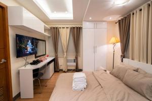a bedroom with a bed with a desk and a television at A2J Luxury 1BR Near Venice Mall BGC Free Pool Use in Manila