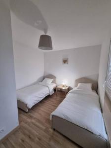a bedroom with two beds and a table with a lamp at VILLA ROSA PARK in Guipavas