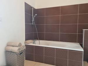 La salle de bains est pourvue d'une baignoire et de carreaux bruns. dans l'établissement VILLA ROSA PARK, à Guipavas
