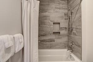a bathroom with a bath tub and a white shower curtain at Modern Condo on South Slope in Asheville +19 photos