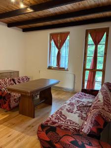 uma sala de estar com uma mesa de madeira e 2 janelas em Domki Carmen em Wierzchownia