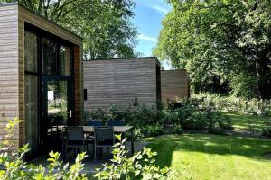 a patio with a table and chairs in a garden at Tiny House Old Oaks in Hulshorst