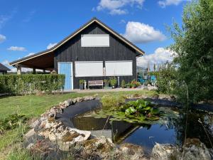 a barn with a pond in front of a house at Het Riethuis in Holthone