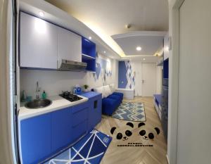 a kitchen with blue cabinets and a blue couch at Apartment Kalibata City by PanBul in Jakarta