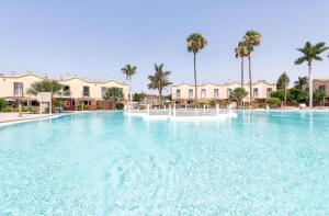 a large swimming pool in a resort with palm trees at MASPALOMAS GREEN OASIS CLUB playa in Maspalomas
