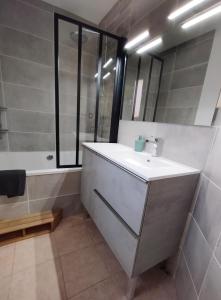 een badkamer met een wastafel, een bad en een spiegel bij Maison calme à proximité du Lac in Savines
