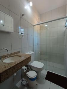 Baño blanco con aseo y lavamanos en Residencial Caramujo, en Florianópolis