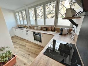 una cocina con armarios blancos, ventanas y una mesa. en Le grand cocon - Coeur de ville, en La Rochelle 4 fotos más