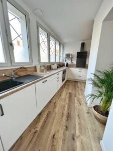 cocina con armarios blancos y suelo de madera en Le grand cocon - Coeur de ville, en La Rochelle