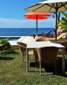 Casa De Amed في آميد: طاولة وكراسي مع مظلات بجوار المحيط