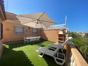 een patio met een tafel en stoelen en een parasol bij Casa Doñana Golf in Matalascañas