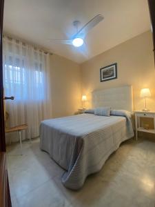 a bedroom with a large bed and a ceiling fan at Casa Doñana Golf in Matalascañas