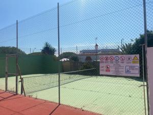 una pista de tenis con un cartel en una valla en Casa Doñana Golf, en Matalascañas