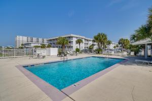 a swimming pool at a resort with palm trees and a building at Gulf Shores Condo with Private Balcony on the Beach! in Gulf Highlands
