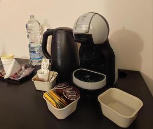 una macchinetta del caffè nera seduta su un tavolo con contenitori di il Sole di Baggio a Milano
