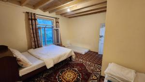 um pequeno quarto com uma cama e uma janela em Karakorum Family Guest House Hunza em Hunza