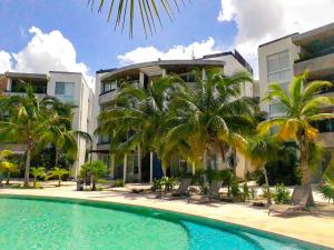 a swimming pool in front of a building with palm trees at Citnos Luxury Accommodation in Telchac Puerto