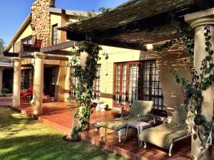 a patio with two chairs and a pergola at MacGregors Guest House in Pretoria