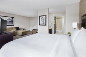 a bedroom with a large white bed and a living room at Residence Inn Boston Franklin in Franklin